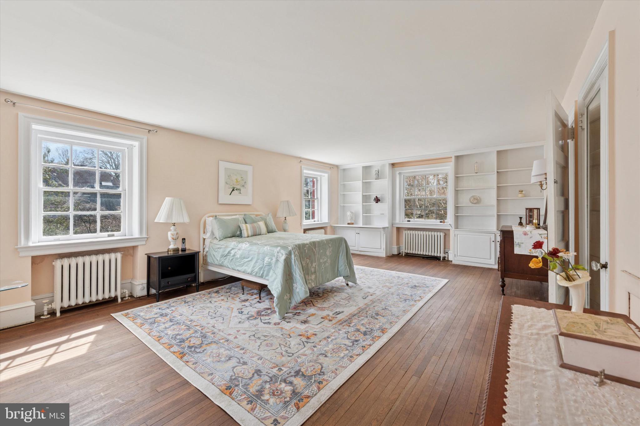 402 Penn Road Wynnewood, PA 19096 - Photo 45 of 75 a spacious bedroom with a bed a couch and large window with wooden floor