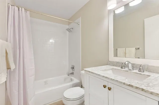 a bathroom with a granite countertop sink a toilet and shower