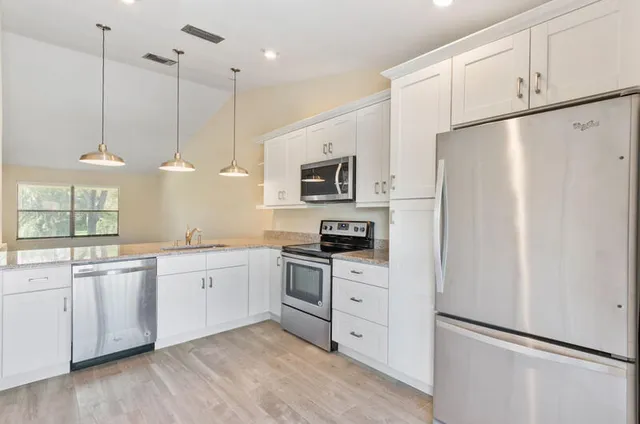 a kitchen with granite countertop cabinets stainless steel appliances and a chandelier
