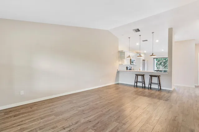 a view of an empty room with a window and wooden floor