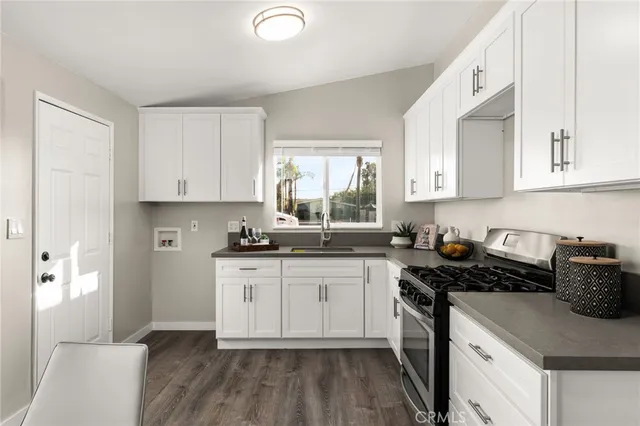 a kitchen with a sink a stove cabinets and wooden floor