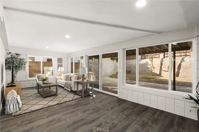 a living room with furniture large windows and wooden floor