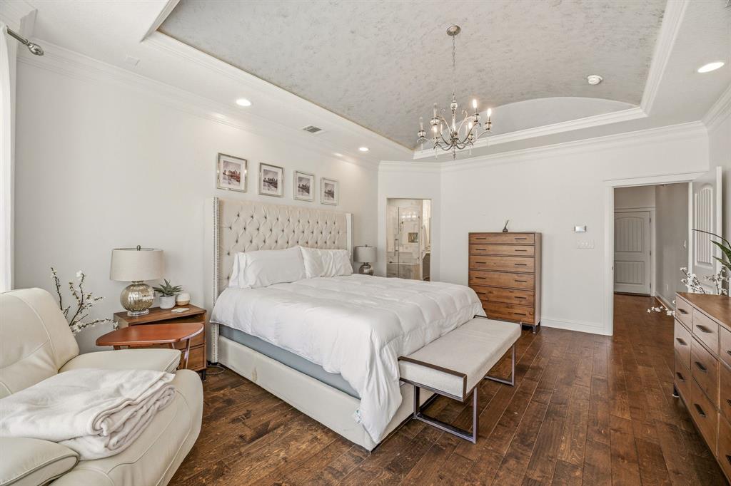 2009 Tree Top Court Granbury, TX 76049 - Photo 22 of 40 a spacious bedroom with a bed a chandelier and a television
