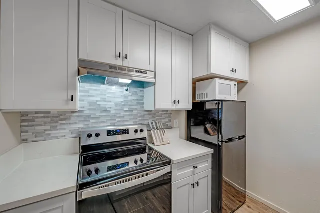 a kitchen with a stove and white cabinets