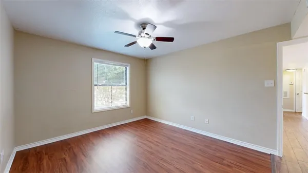 a view of an empty room with wooden floor and a window