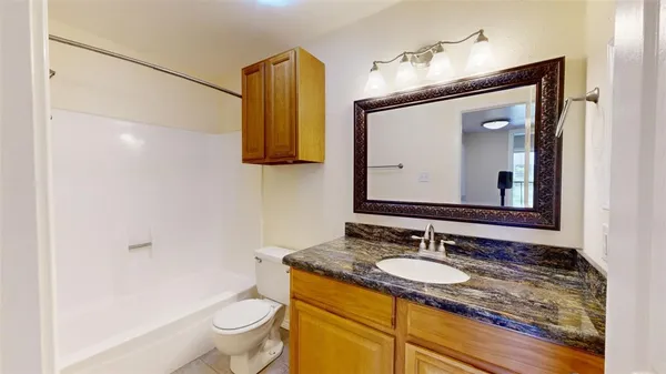 a bathroom with a granite countertop sink vanity mirror and toilet
