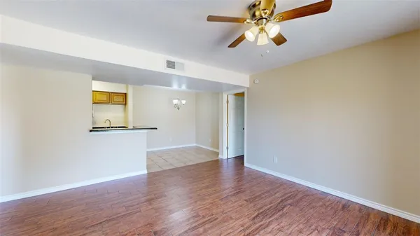 a view of a big room with wooden floor and a chandelier fan
