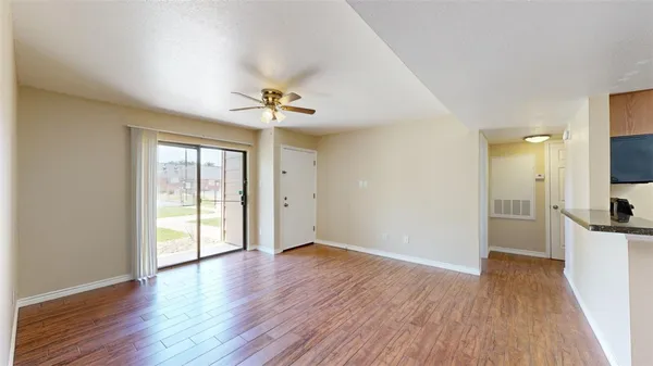 a view of an empty room with a window and wooden floor