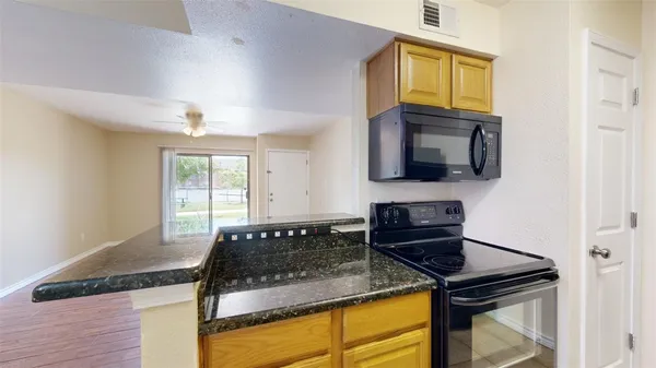 a kitchen with granite countertop a sink stainless steel appliances and window