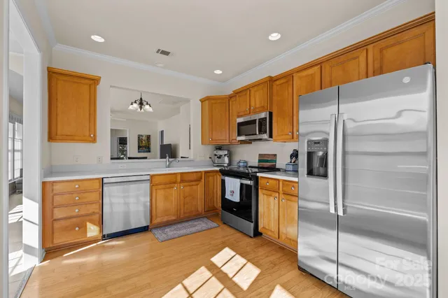a kitchen with stainless steel appliances granite countertop a refrigerator a stove top oven and sink