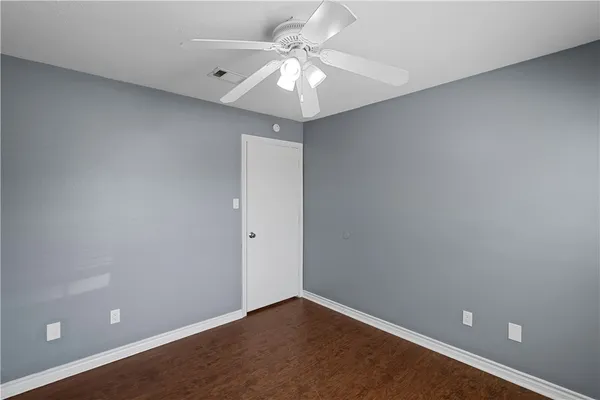 an empty room with a chandelier fan and windows