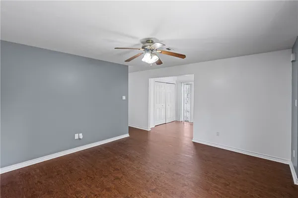 a view of a room with wooden floor and a ceiling fan