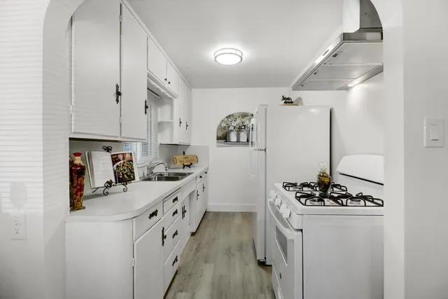 a kitchen with refrigerator a stove and white cabinets