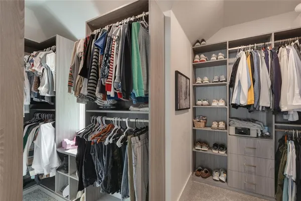 a view of walk in closet with clothes and shoes