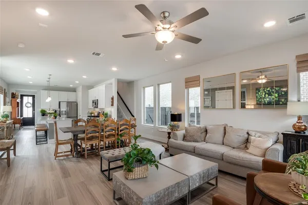 a living room with furniture kitchen view and a wooden floor