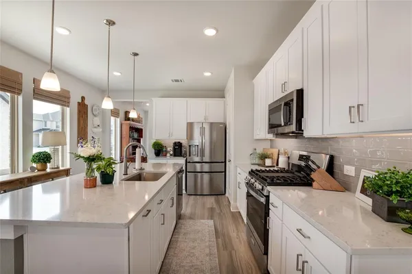 a kitchen with stainless steel appliances a sink a stove top oven a counter space and cabinets