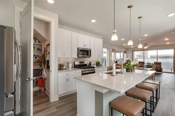 a kitchen with stainless steel appliances kitchen island granite countertop a stove top oven a sink a dining table and chairs with wooden floor