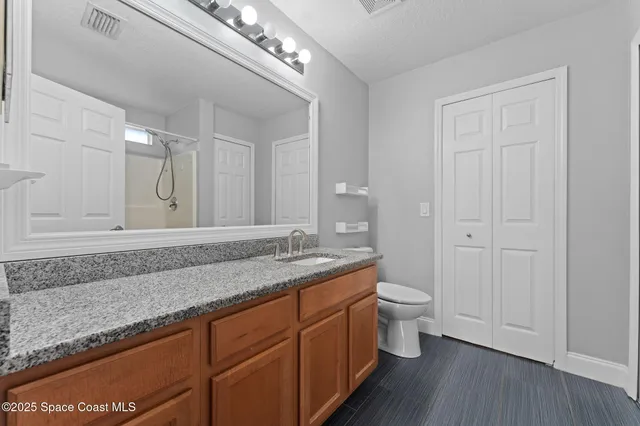 a bathroom with a granite countertop sink a toilet and a mirror
