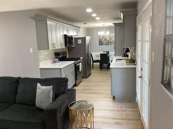 a living room with furniture a large window and wooden floor
