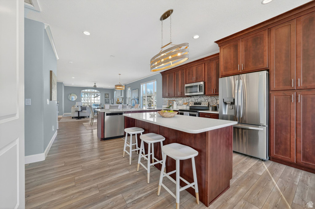 1222 West 190th Street North Mapleton, UT 84664 - Photo 12 of 46 Spacious kitchen featuring a central island with white countertop, rich wood-finish cabinetry, stainless steel appliances, and wood-finish flooring