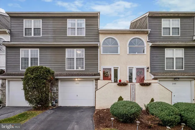 a view of a white house with large windows and plants
