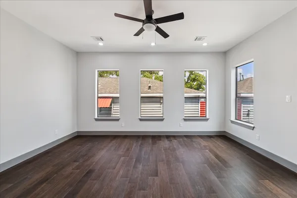 an empty room with wooden floor and windows