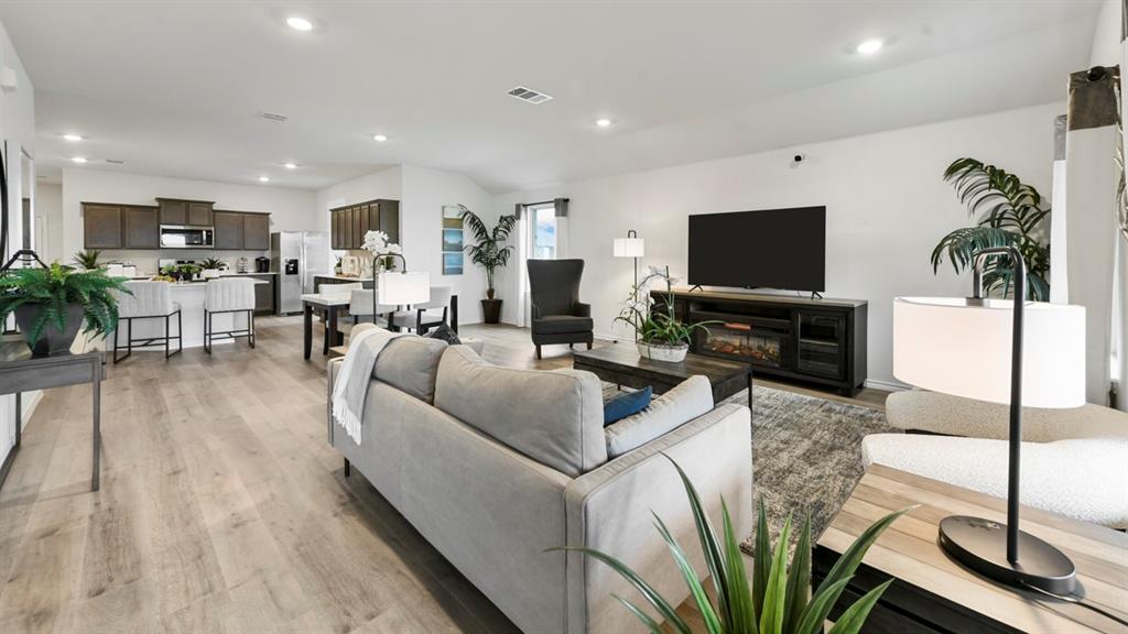1671 Mantle Road Crandall, TX 75114 - Photo 7 of 24 Open-concept living area featuring wood-finish flooring, recessed lighting, and a modern kitchen with dark cabinetry and stainless steel appliances