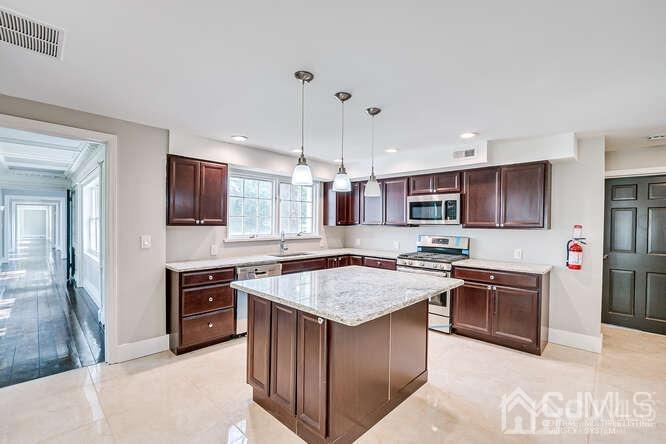 55 Devon Road, Unit B Colonia, NJ 07067 - Photo 28 of 53 a kitchen with stainless steel appliances granite countertop a stove top oven a sink dishwasher a refrigerator and a dining table with wooden floor