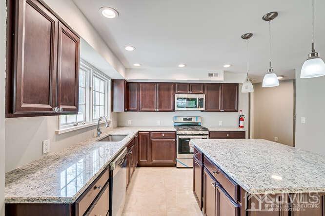55 Devon Road, Unit B Colonia, NJ 07067 - Photo 29 of 53 a kitchen with stainless steel appliances granite countertop a kitchen island a stove a sink and a refrigerator