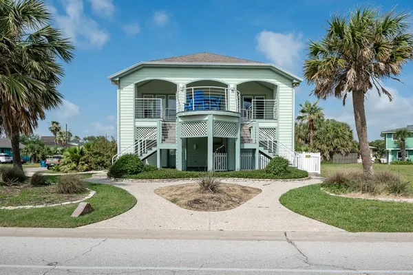 front view of house with a yard and palm trees