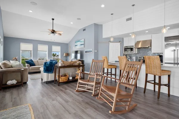 a living room with furniture and a dining table with wooden floor
