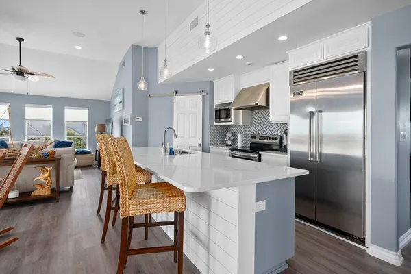 a kitchen with stainless steel appliances kitchen island granite countertop a table chairs refrigerator and microwave