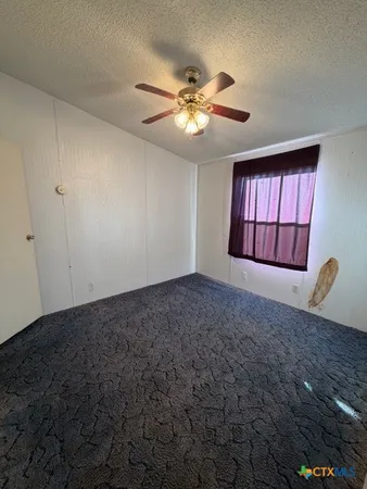 a view of a livingroom with a chandelier fan and windows