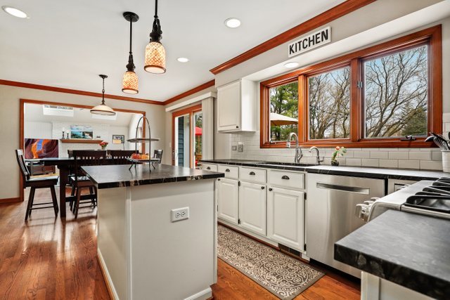 982 Plum Tree Road Fox River Grove, IL 60021 - Photo 7 of 48 a kitchen with granite countertop a stove a sink a dining table and chairs with wooden floor