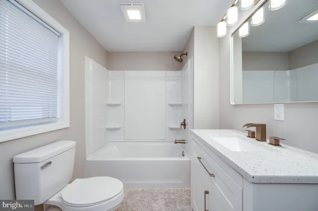 a bathroom with a sink a toilet a mirror a bathtub and shower