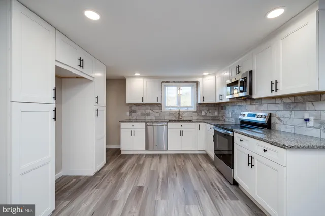 a large kitchen with a white cabinets and wooden floor