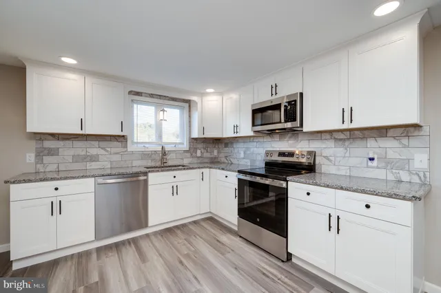 a kitchen with granite countertop white cabinets white appliances sink and dishwasher