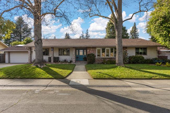 a view of a house with a yard and large tree