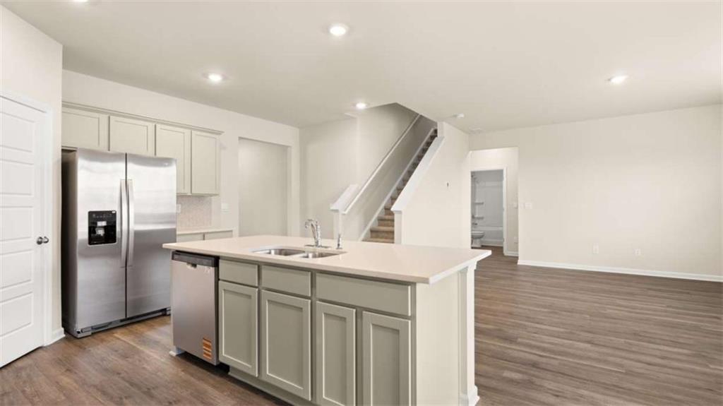 100 Planters Row Perry, GA 31069 - Photo 11 of 37 a kitchen with a sink a refrigerator a stove and white cabinets with wooden floor