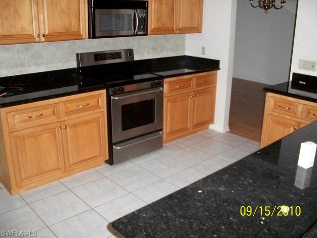 240 9th Street Southwest Naples, FL 34117 - Photo 4 of 8 a kitchen with granite countertop white cabinets and black appliances
