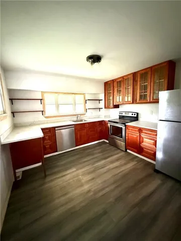 a kitchen with stainless steel appliances granite countertop a sink dishwasher and a refrigerator with wooden floor
