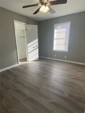 an empty room with wooden floor cabinet and windows