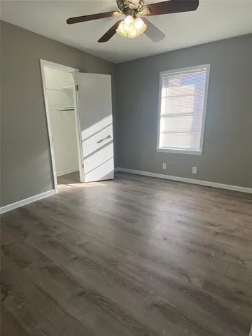 an empty room with wooden floor cabinet and windows