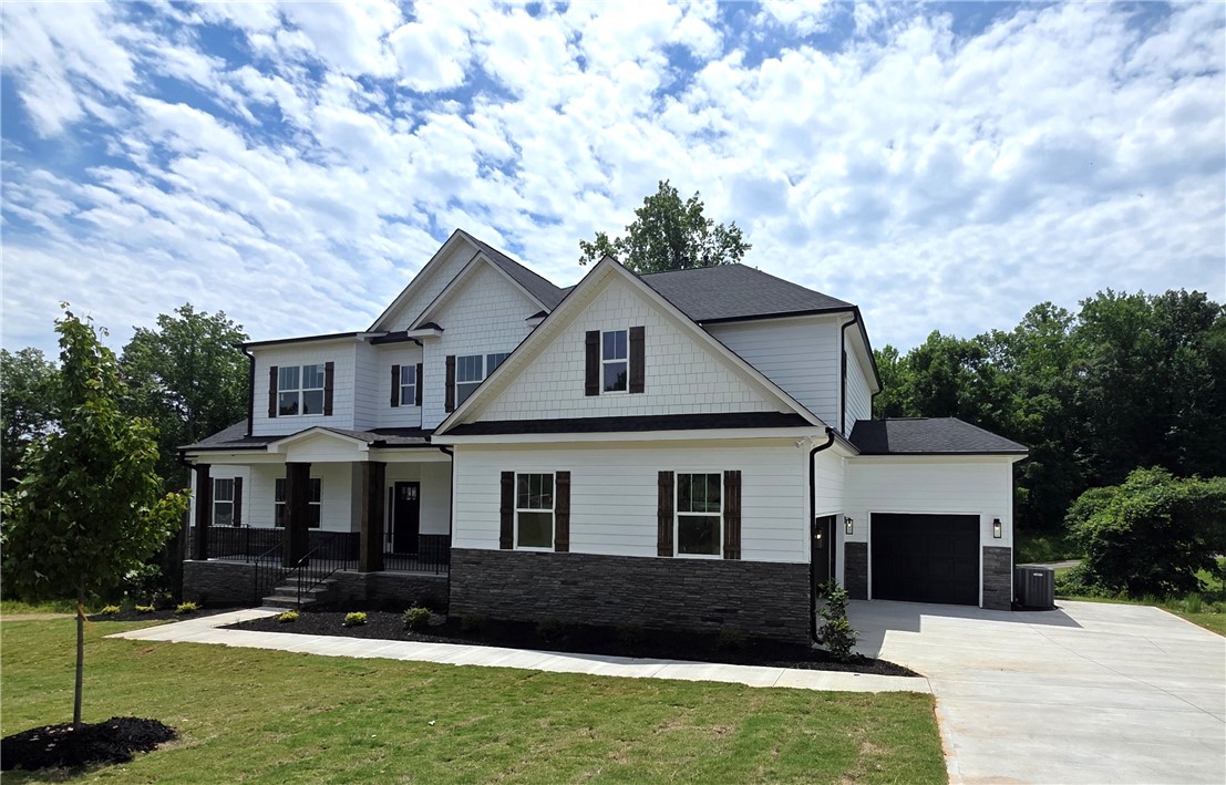 243 Holly Br Road Piedmont, SC 29673 - Photo 2 of 21 A newly constructed residence showcasing classic gables, a welcoming covered porch, and a practical two-car garage.