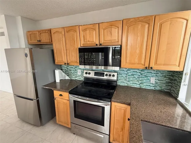 a kitchen with stainless steel appliances granite countertop a refrigerator stove and microwave