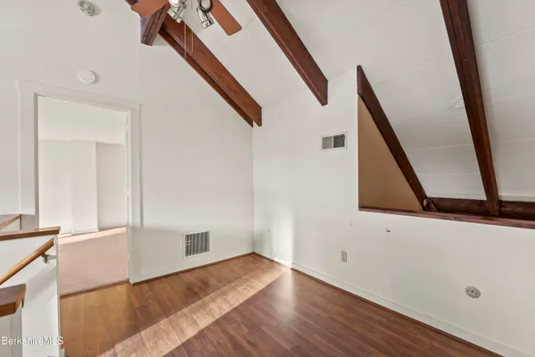 a view of an empty room with wooden floor and stairs