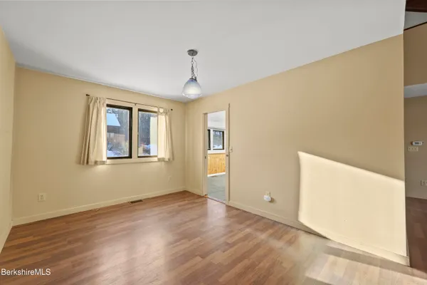 a view of an empty room with window and wooden floor