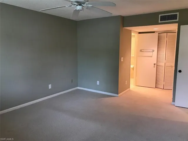 an empty room with a ceiling fan and a window