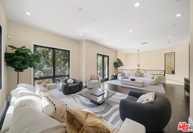 a living room with furniture large window and potted plants