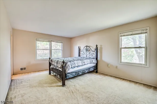 a bed sitting in a spacious bedroom next to a window and a dresser